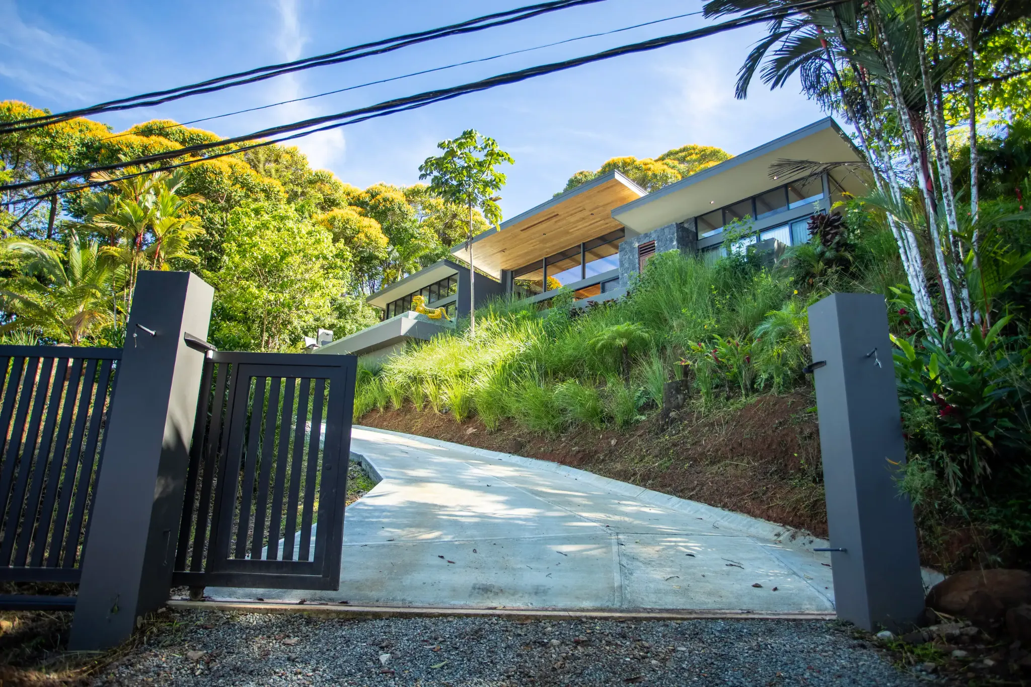 Casa de Olas above its gated driveway, surrounded by tropical greenery