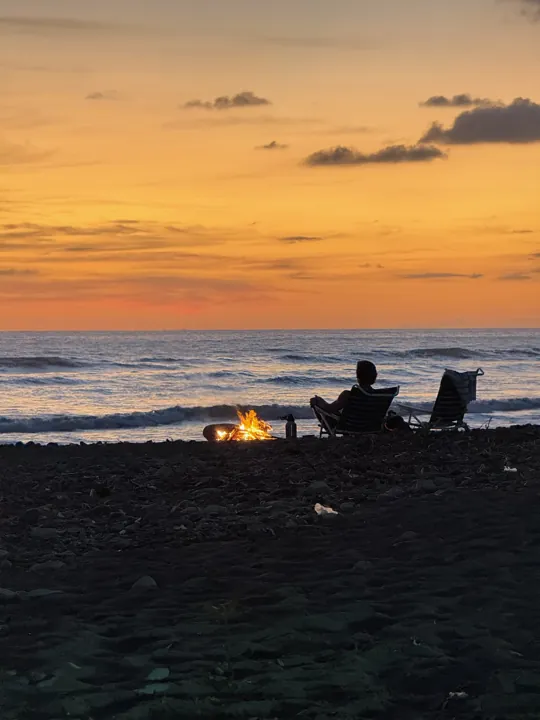 Beach chairs and a small fire at sunset
