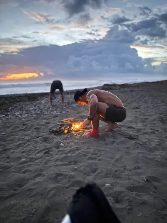 People tending a small beach fire at dusk