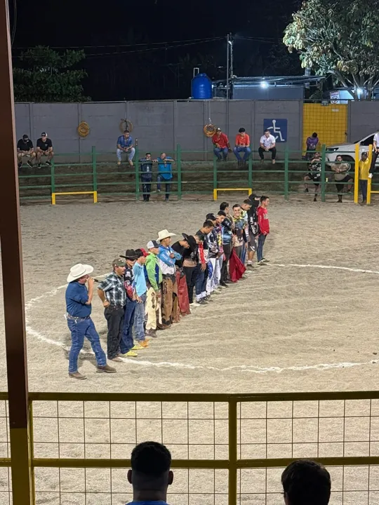 People gathered along a fence in a lit arena at night
