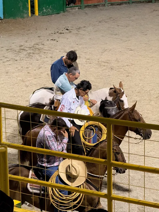 Horseback riders beside the fence of an arena