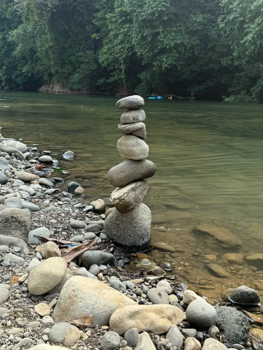 Stacked smooth stones beside a shallow forest river