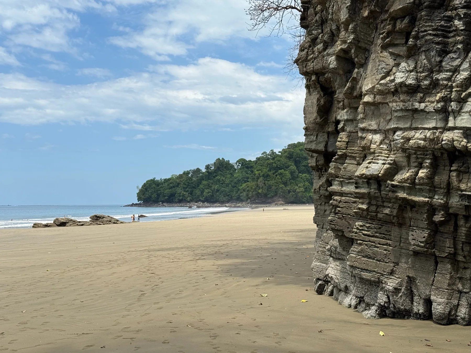 Wide sandy beach beside layered rock cliffs