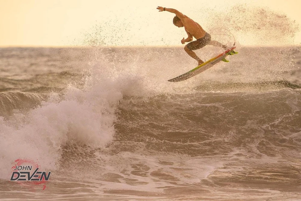 A surfer launching above a golden wave
