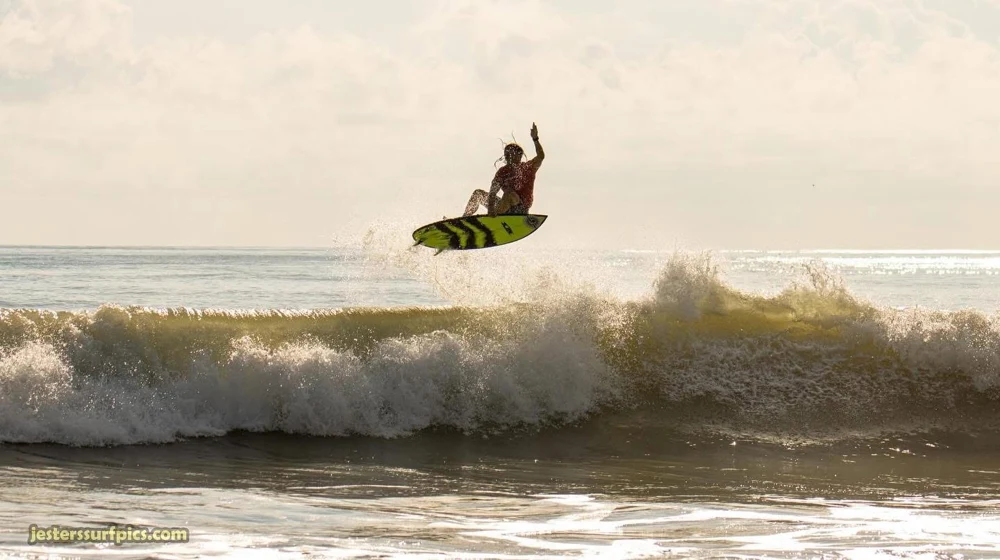 A surfer airborne on a green board