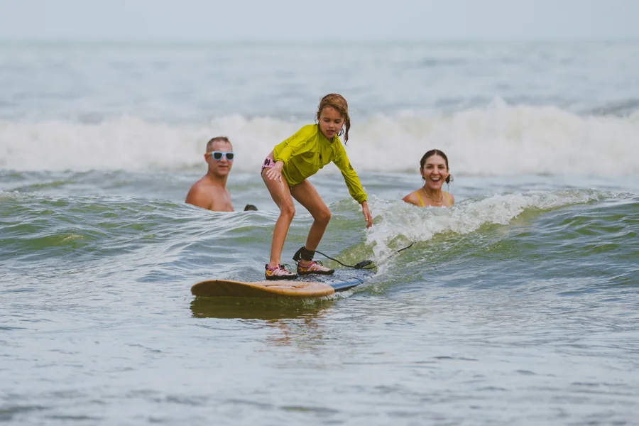 A young surfer with support nearby