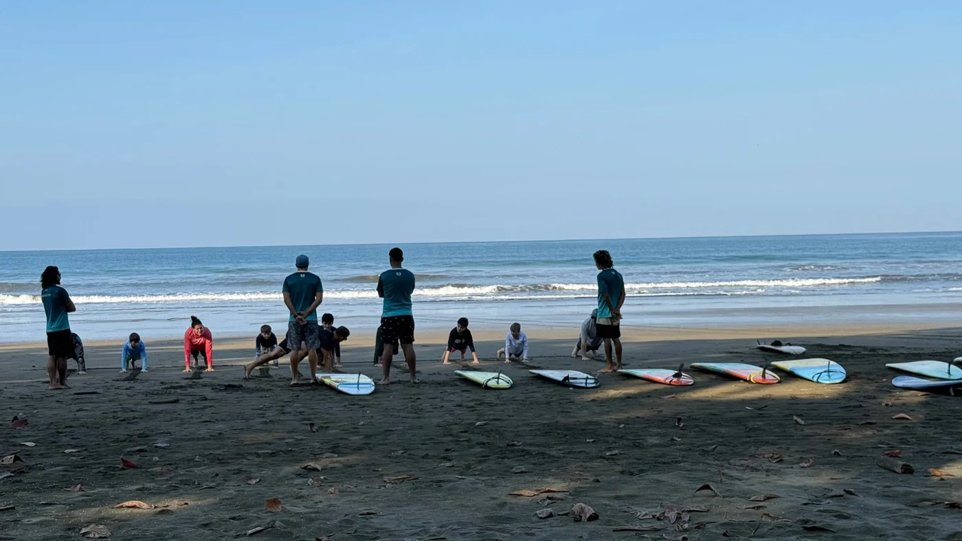 Surf students practicing on the beach with Flow instructors and boards nearby
